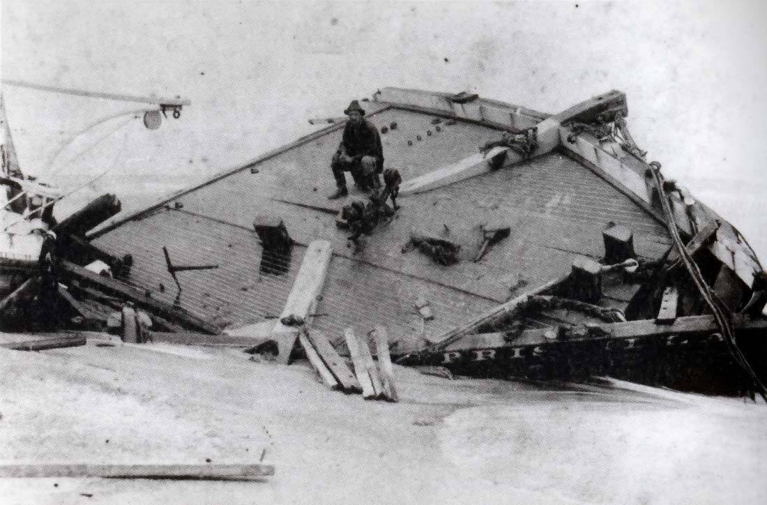 4.	Photo of Surfman Rasmus Midgett seated on the beached bow section of the Priscilla after the hurricane had passed. (National Park Service)