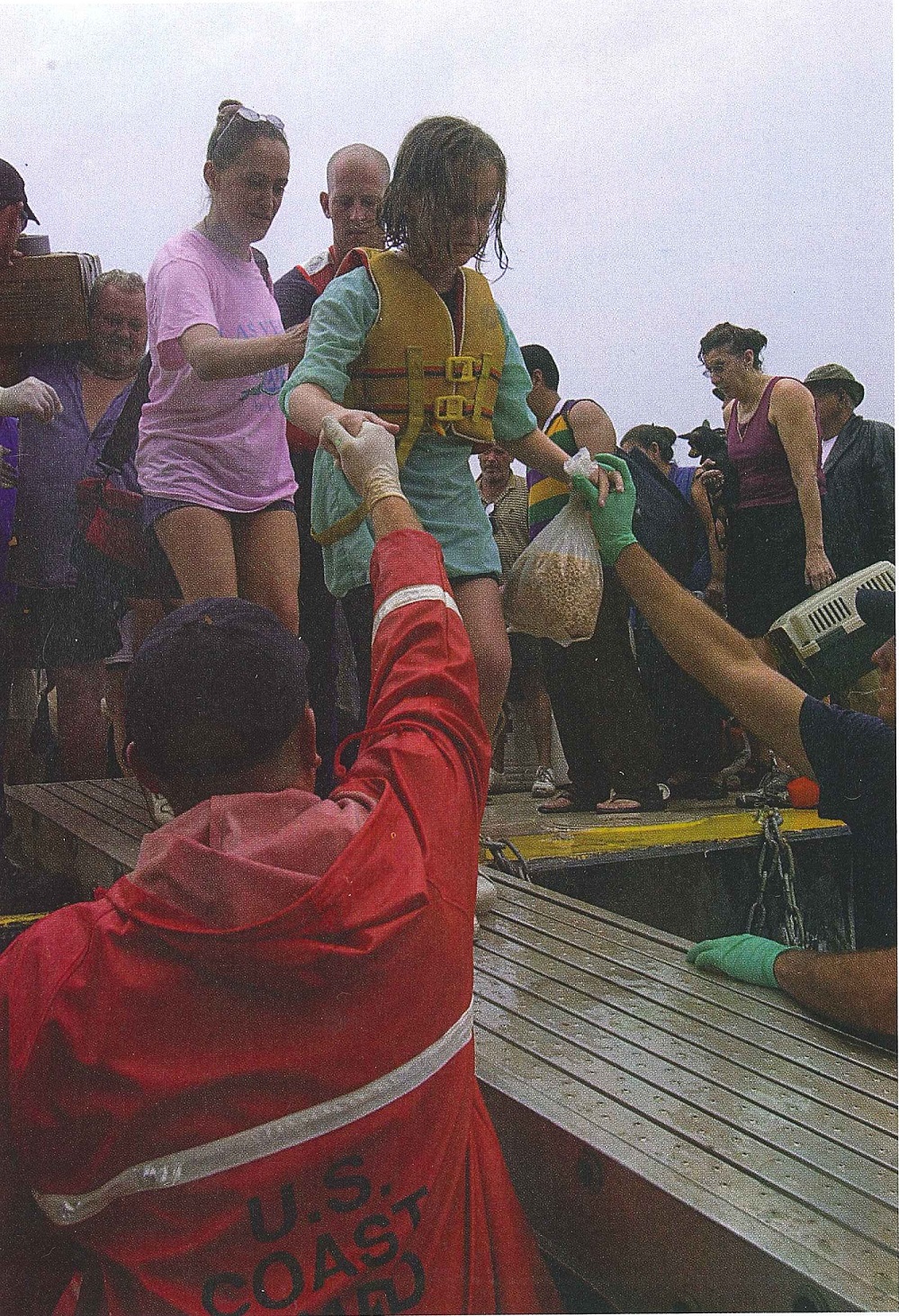 7.	Coast Guard personnel assist displaced persons disembarking the evacuation barge. (U.S. Coast Guard)